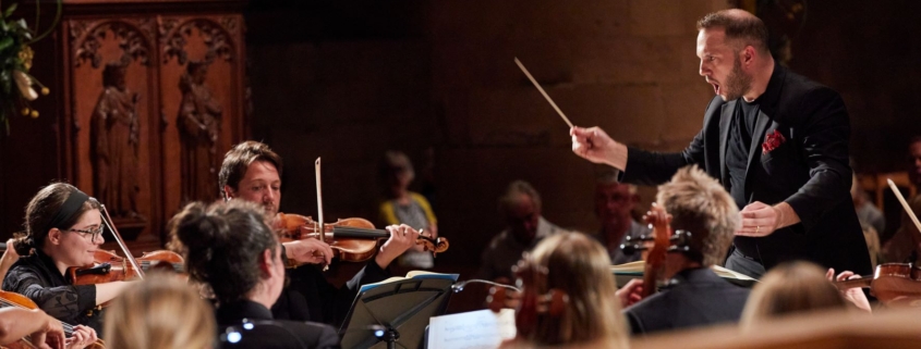 Marcus Farnsworth conducting a group of musicians in Southwell Minster