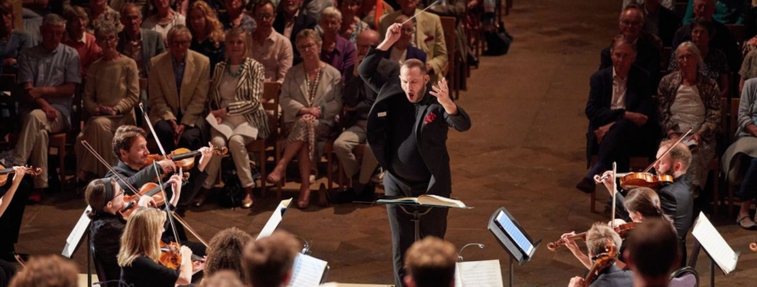 Marcus Farnsworth conducting musicians playing in the Festival Sinfonia in a packed Southwell Minster.