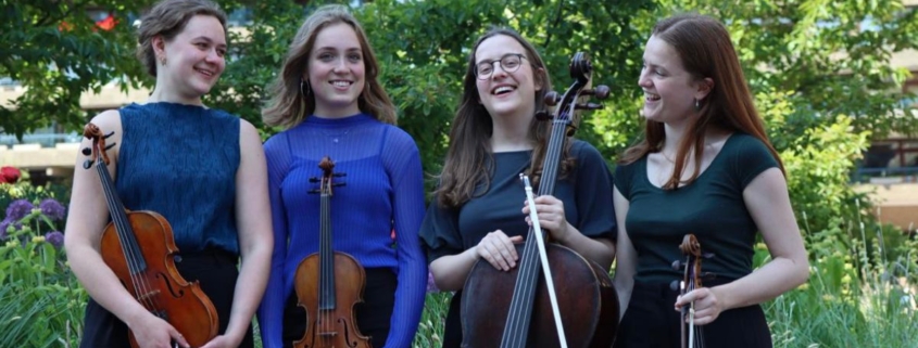 Four young string players stood together outside holding their instruments and laughing.