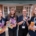 Four Festival Makers stood tofether outside the Trebeck Hall, holding Festival merchandise and programme books