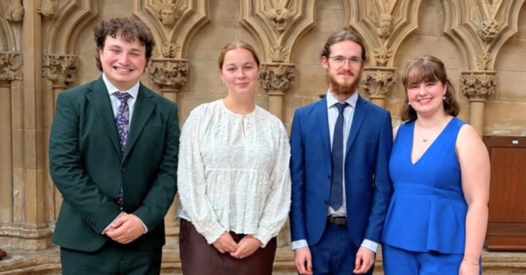 Four young singers, wearing smart clothing, stood together for a photo in Southwell Minster.
