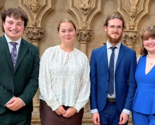Four young singers, wearing smart clothing, stood together for a photo in Southwell Minster.