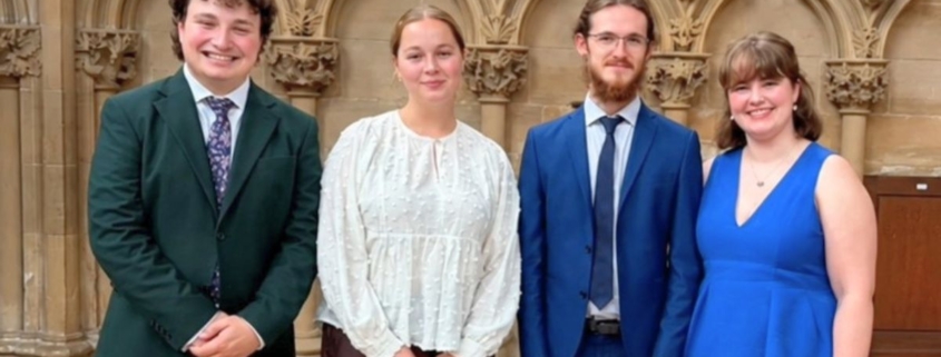 Four young singers, wearing smart clothing, stood together for a photo in Southwell Minster.